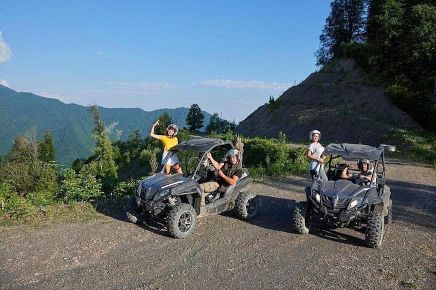 Three off-road vehicles on a gravel road with a mountainous landscape in the background. 5