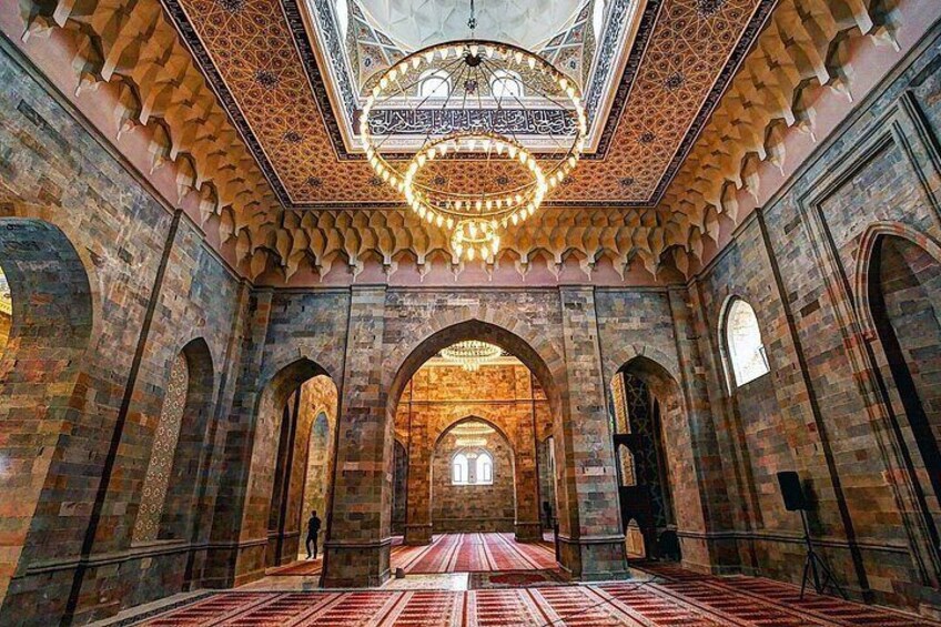 A mosque interior with arched doorways, a patterned ceiling, and a carpeted floor. 2