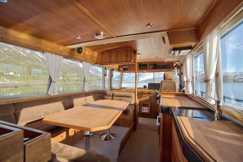 A cozy interior with wooden furniture, a dining table, and large windows overlooking a scenic landscape. 2