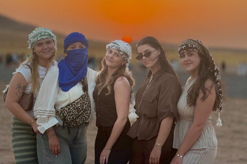 A group of people standing in a desert landscape with a sunset in the background. 2