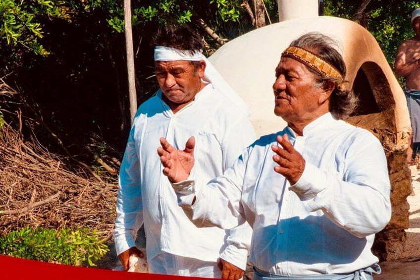 Two individuals in white shirts standing outdoors with a large earthen structure in the background. 5