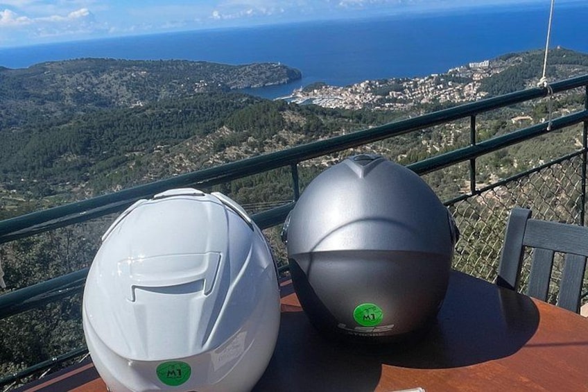 Deux casques sont posés sur une table, offrant une vue panoramique sur un paysage côtier. 3
