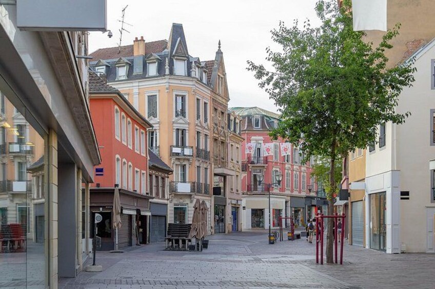 A cobblestone street lined with historic buildings, a tree, and a red pole. 3