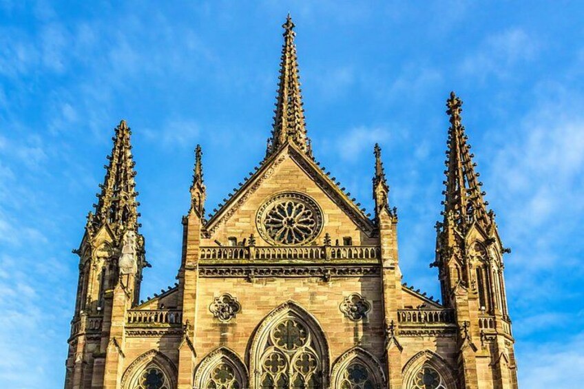 A Gothic cathedral with a large circular clock, pointed spires, and intricate stone carvings. 1