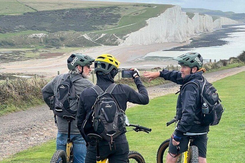A group of cyclists on a trail with a coastal landscape in the background. 5