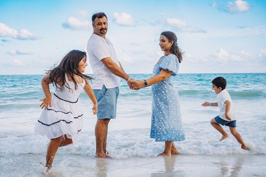 En familie på fire på en strand med havet i baggrunden. 4
