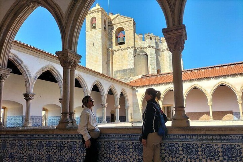 An architectural courtyard with arches and a tower in the background. 3