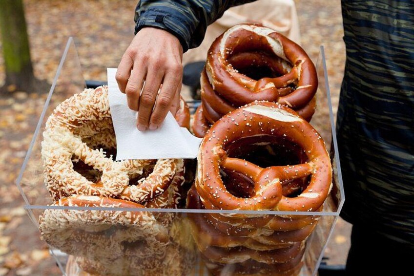 A person holding a napkin over a clear plastic container filled with pretzels. 2