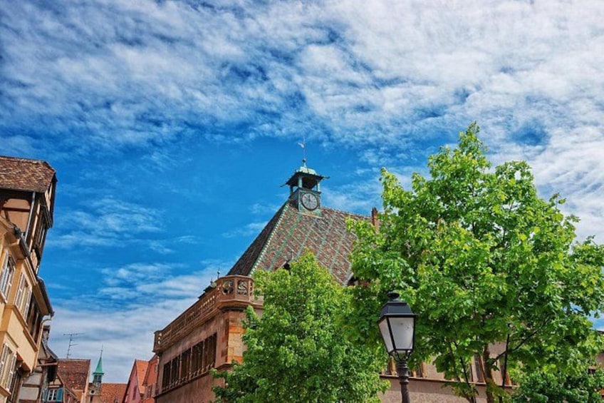 A historic building with a clock tower, surrounded by trees and under a blue sky with clouds. 4
