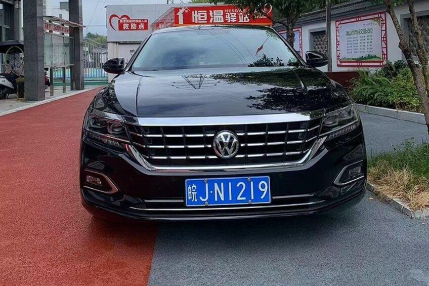 A black Volkswagen car with a blue license plate on a road. 4