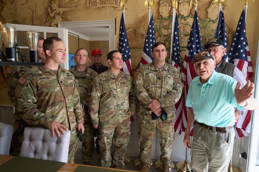 Militairen in uniform staan in een ruimte met Amerikaanse vlaggen en een trofee. 2