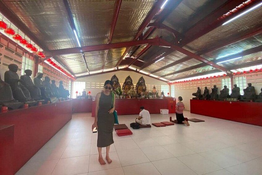 Innenraum eines Tempels mit meditierenden Personen, einer Gottheit-Statue und einem roten Altar. 3