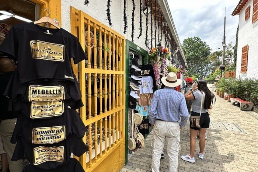 A street with a shop displaying t-shirts and a man taking a photo. 2