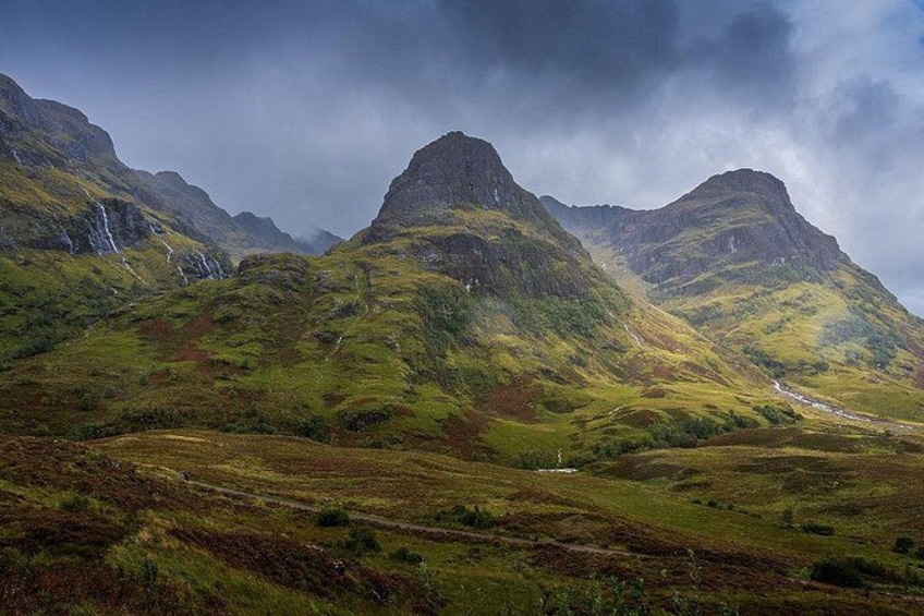 A mountainous landscape with a winding road and a waterfall. 3
