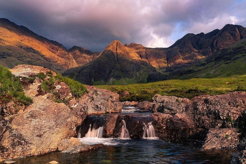 A mountainous landscape with a waterfall, rocky terrain, and lush greenery. 4
