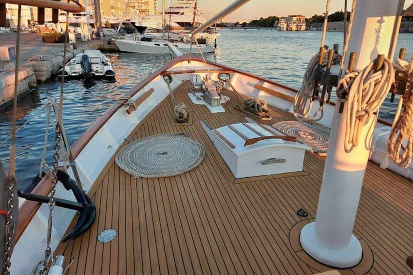 A wooden deck with ropes, a steering wheel, and a lifebuoy on a boat. 2