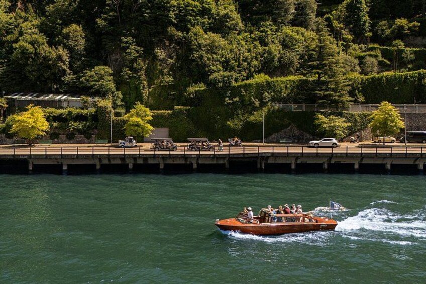 A boat with passengers on a river, surrounded by greenery and a bridge. 3
