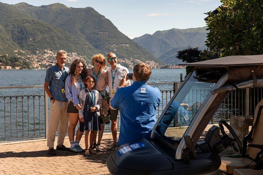 A group of people standing by a body of water with mountains in the background. 5