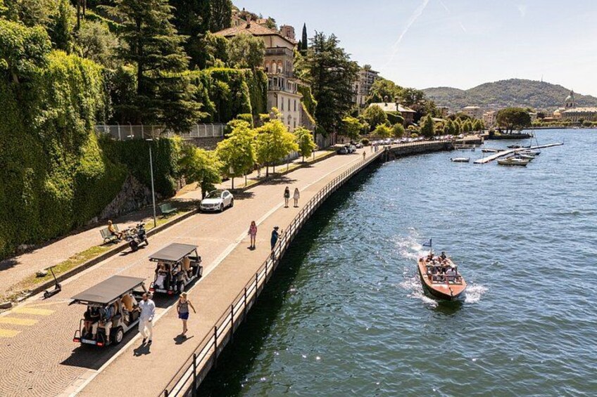 A river with a boat, a paved walkway, and buildings along the riverbank. 2