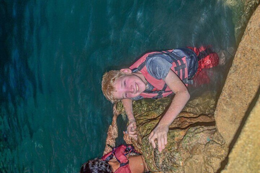 A person in a red life jacket near a rocky cliff edge. 5