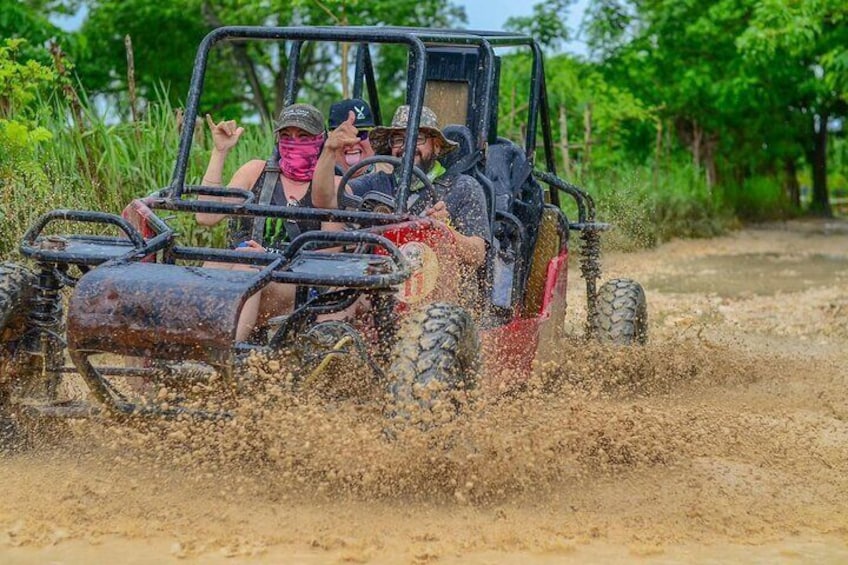 A four-wheeled vehicle driving through a muddy area, kicking up mud. 1