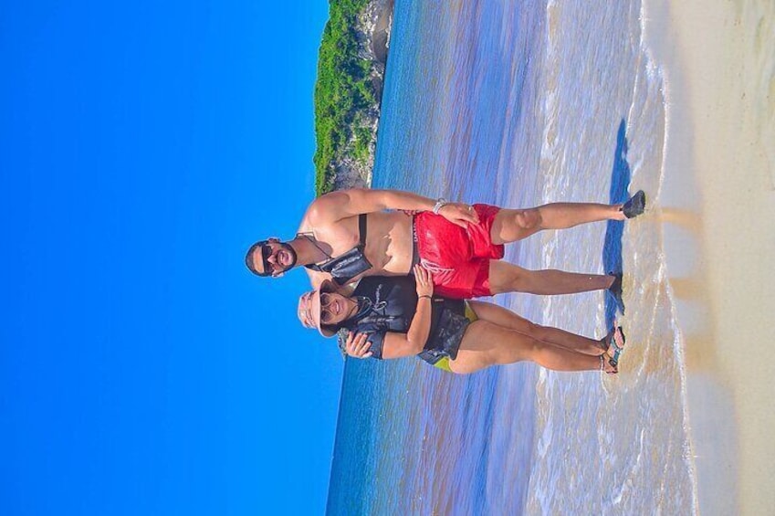 Two people standing on a beach with waves in the background. 4