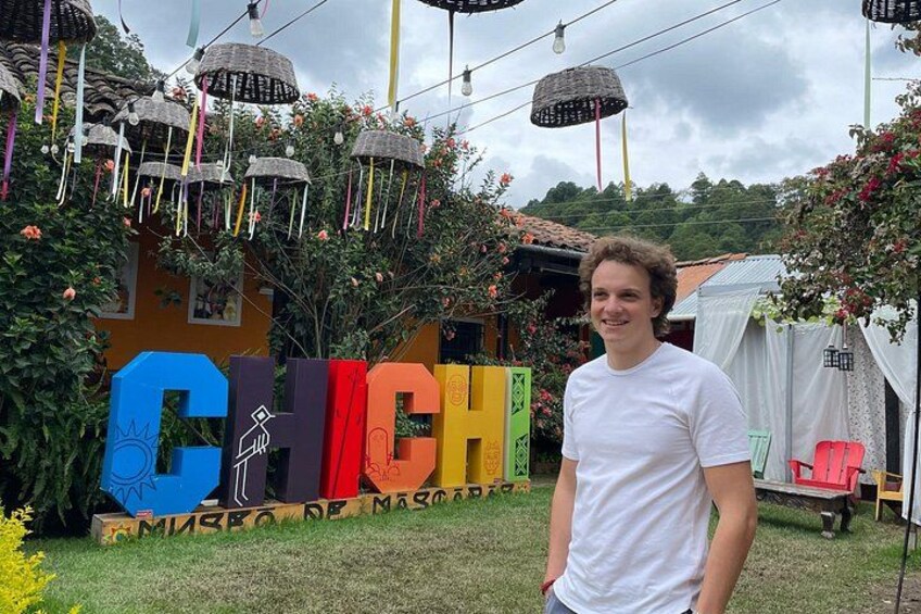 A person standing in front of a colorful sign with the word 'CHICH' partially visible. 2