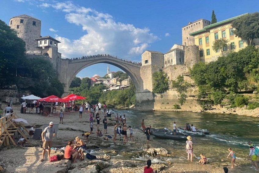 A historic stone bridge, a river, and people engaging in water activities. 5