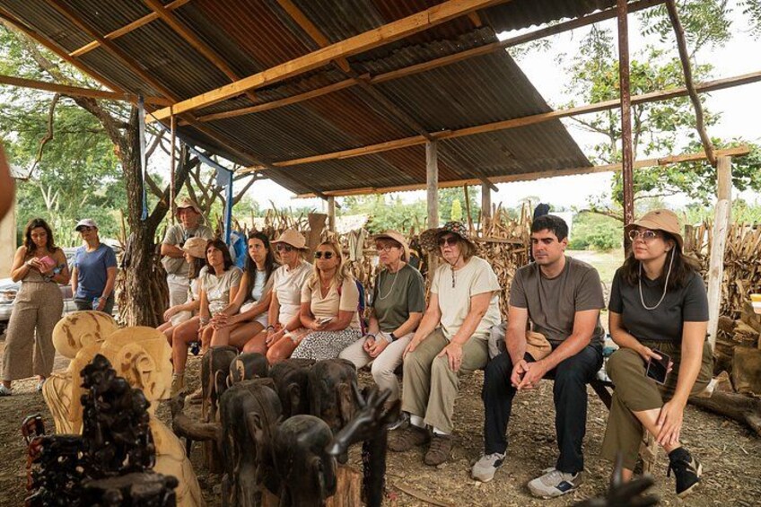 A group of people sitting under a shelter with animals around them. 2