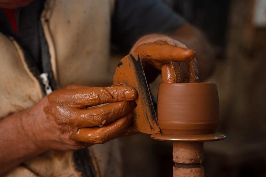 A person shaping a clay pot on a pottery wheel. 5