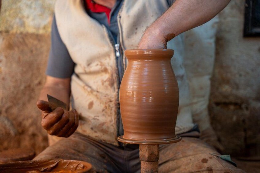 A person shaping a clay pot on a pottery wheel. 4