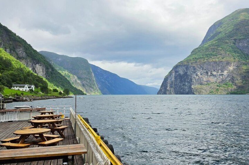 A wooden pier with benches extending into a fjord, surrounded by steep cliffs. 2