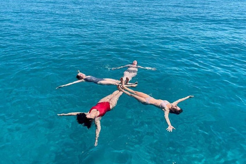 Vier mensen drijven in een heldere blauwe zee. 4