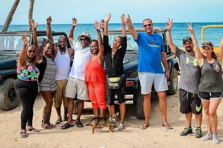A group of people on a beach with a vehicle and a dog. 4