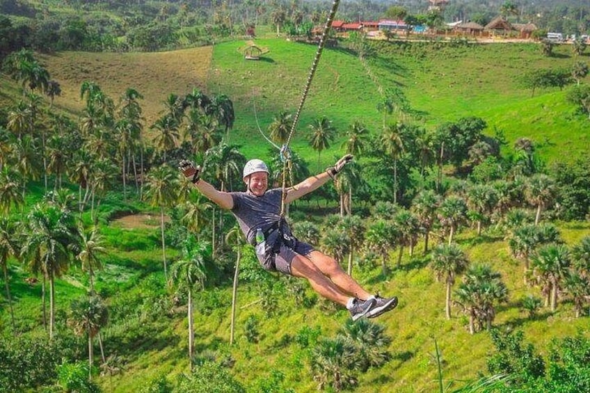 A person zip-lining over a lush green landscape with palm trees. 3