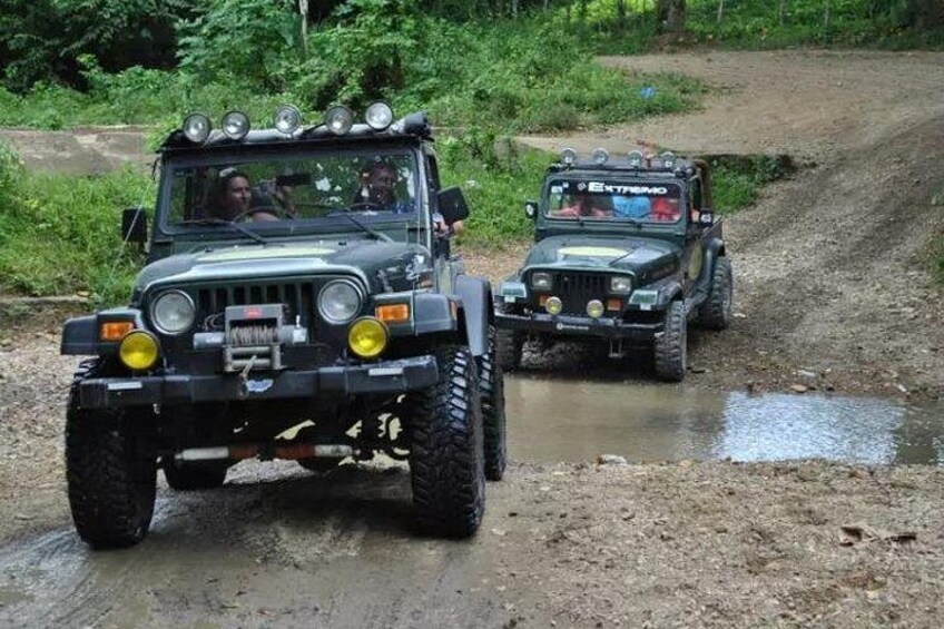 Two off-road vehicles on a muddy path surrounded by greenery. 2