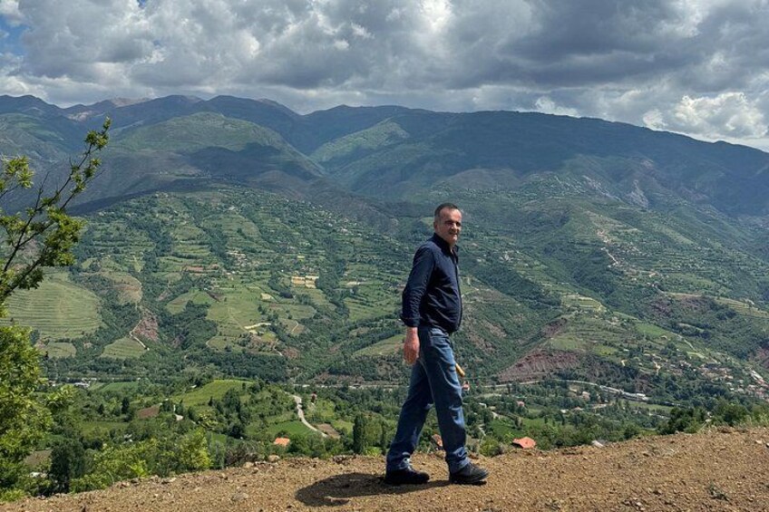 A person standing on a hill overlooking a valley with mountains in the background. 2