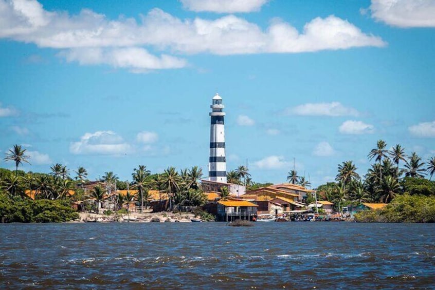 Un faro junto a una ciudad costera con palmeras y edificios. 1