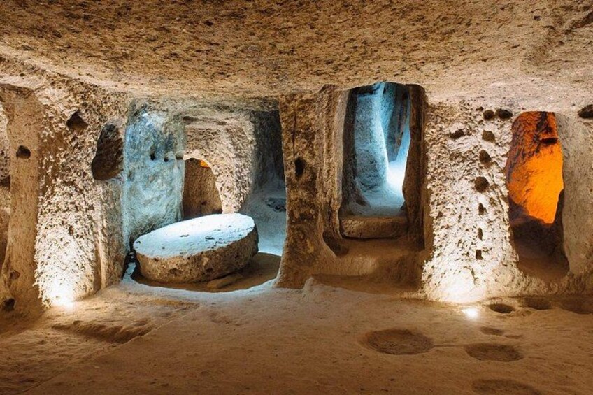 Una cueva antigua con estalactitas, una estructura circular de piedra y un pasaje iluminado con luz azul. 2