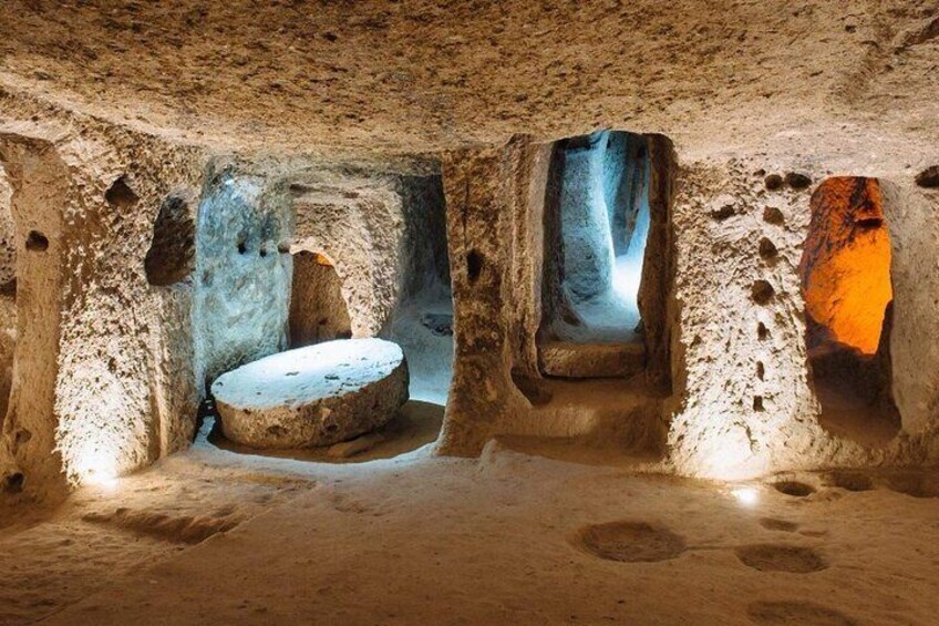 Una cueva antigua con estructuras de piedra y una cuenca de piedra central. 2