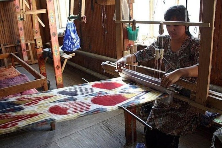 A person weaving on a loom with colorful fabric. 2
