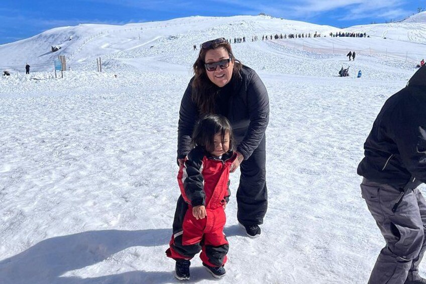 A snowy landscape with a person in a black jacket and a child in a red snowsuit. 4
