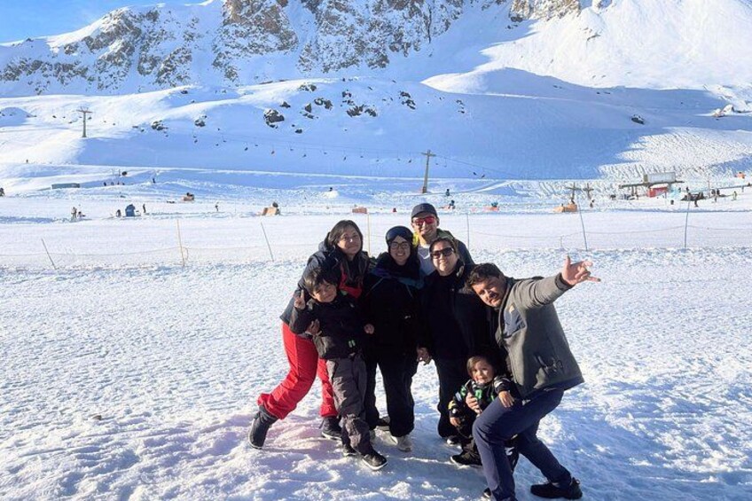 A group of people posing on a snowy mountain with ski lifts in the background. 1
