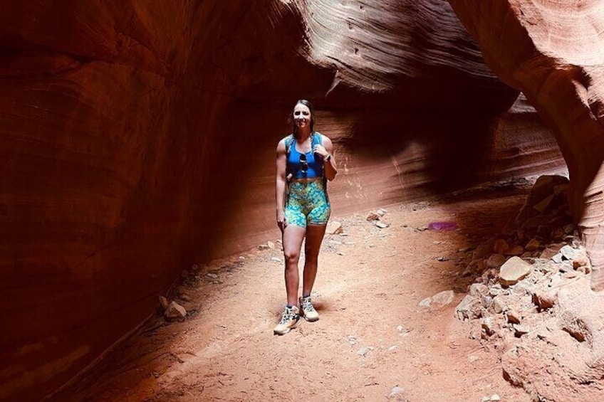 A person hiking in a narrow canyon with reddish rock walls. 1