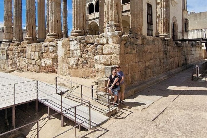 Ancient ruins with columns, a metal staircase, and a paved area. 2