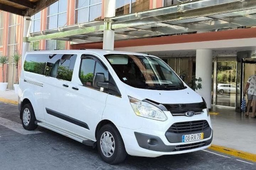 A white van parked in front of a building with a glass entrance. 5