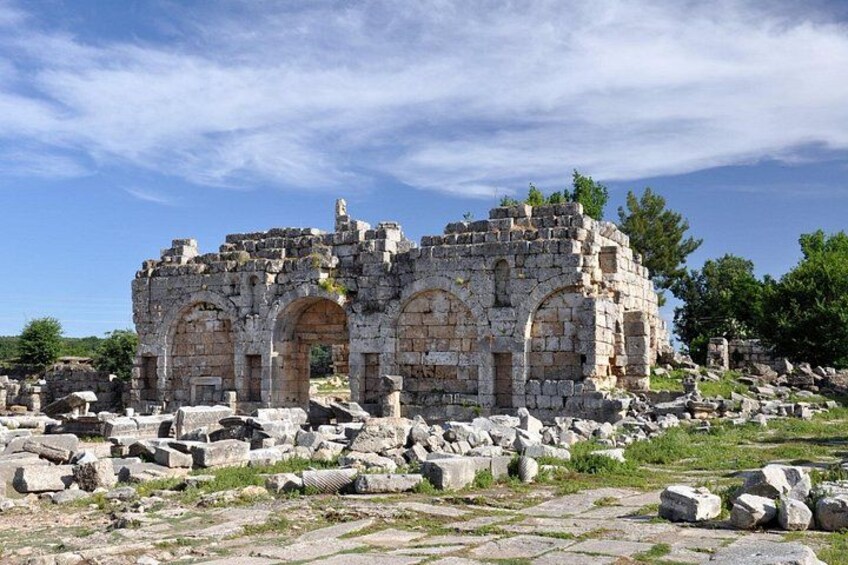 Ancient ruins with stone walls and arches, surrounded by scattered rocks and sparse vegetation. 3