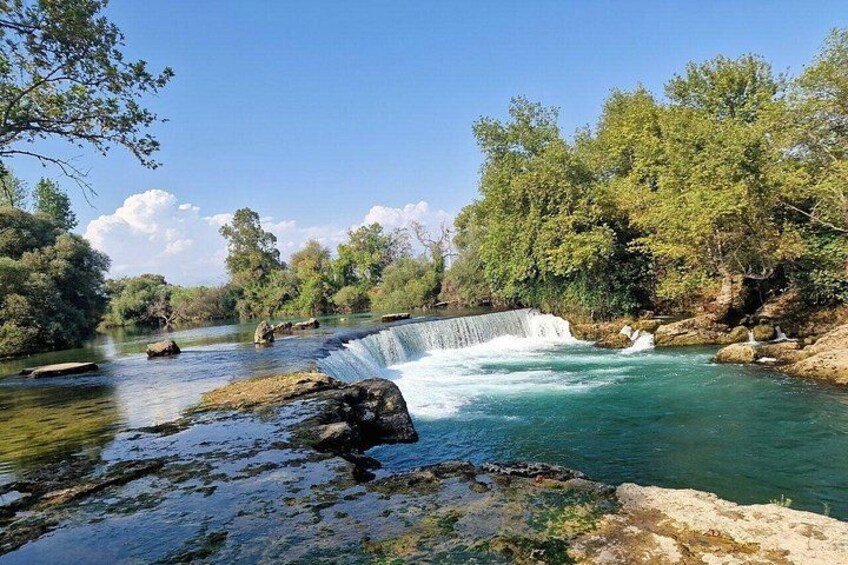 A waterfall, river, and surrounding greenery. 4