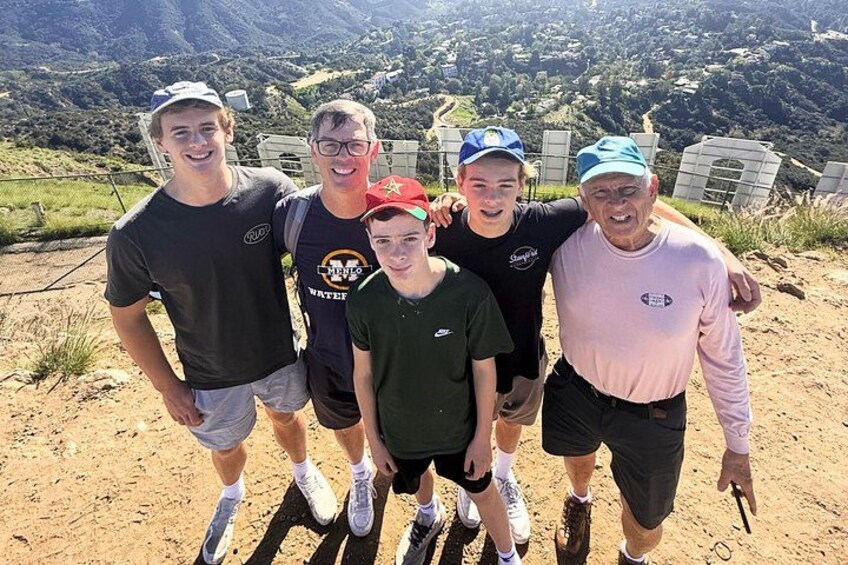 A group of people standing on a dirt path with a mountainous landscape in the background. 2