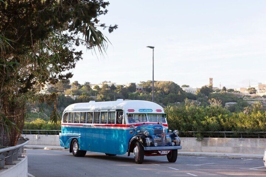 A blue bus with a red and white stripe driving on a road. 2